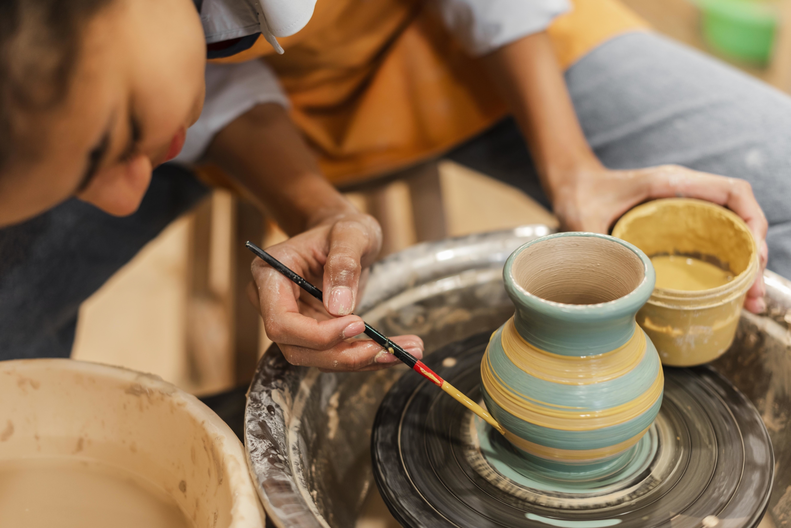 close-up-woman-painting-clay-pot